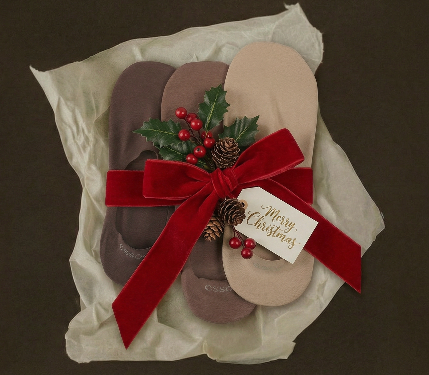 No show socks with a red bow and Christmas decorations on a brown background